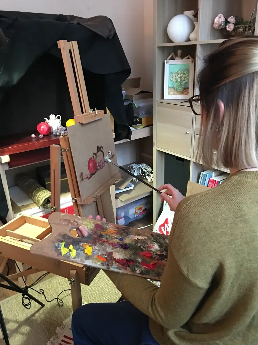 Artist painting at easel with palette